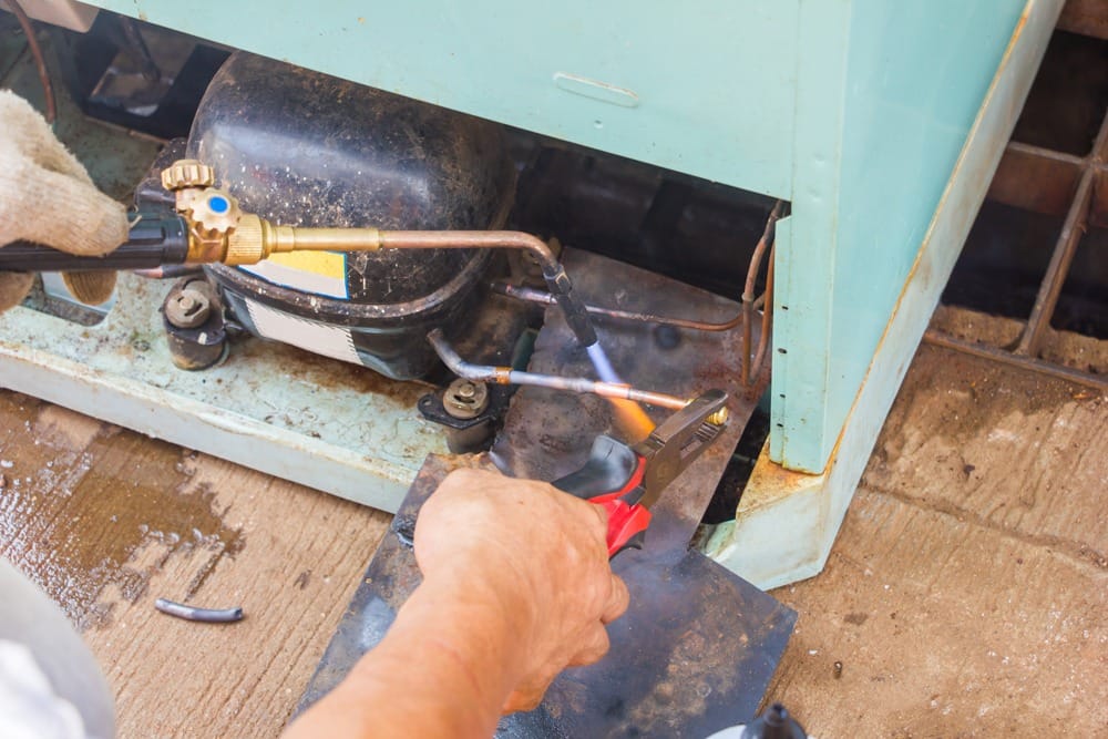 Faulty refrigerator compressor being inspected
