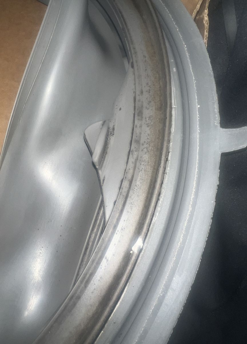 Grey rubber door gasket from a Whirlpool front-load washer, with black mould spots running along the inner fold where water collects